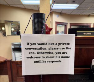 A photo of a tin can with a string coming out of the end. There is a sign that reads, "If you would like a private conversation, please use the can. Otherwise, you are welcome to shout his name until he responds."